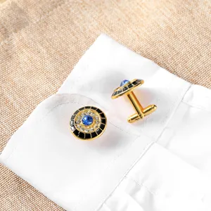 Detailopname van gouden manchetknopen met zwart emaille, strass en blauwe steen.