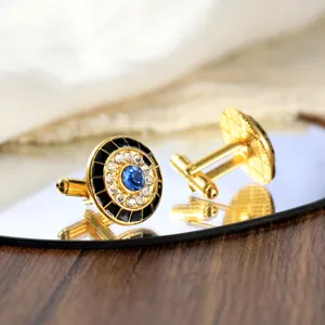 Gedetailleerde close-up van luxe goudkleurige kristallen manchetknopen met blauwe steen.