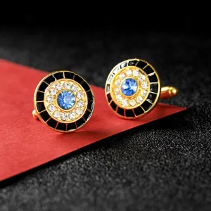 Gedetailleerde close-up van gouden ronde kristallen manchetknoppen met blauwe steen.