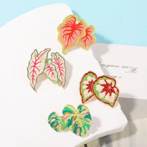 Exquisite tropical plant brooch details showcasing colorful caladium and monstera leaves enamel pins.