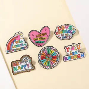 Gros plan détaillé d'un ensemble de badges en émail métallique coloré avec des citations inspirantes.
