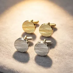 Detailaufnahme von runden Herren-Manschettenknöpfen aus Metall mit Spiralmuster in Gold und Silber.
