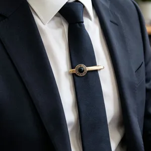 Pince à cravate dorée vintage pour homme avec pierre noire et design circulaire gravé.
