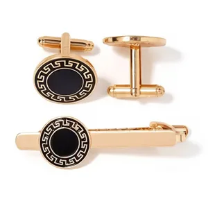 Ensemble de boutons de manchette et pince à cravate dorés vintage avec centre noir et motif.