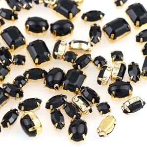 Detailopname van zwarte klauwstrassteentjes met gouden zetting voor knutselkleding.