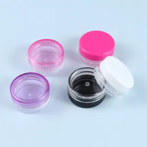 Piccoli barattoli cosmetici in plastica con coperchi colorati per creme e unguenti.