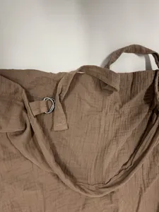 Close-up detail of soft brown double gauze cotton nursing cover and metal adjustment D-ring.