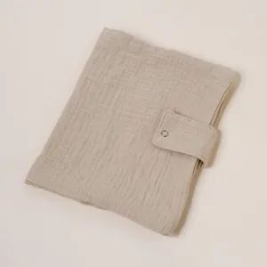 Detalle de la funda para cuaderno de gasa de algodón beige con botón a presión fino.