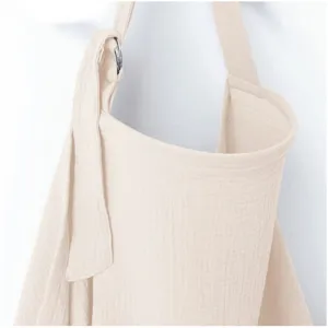 Detail van beige katoenen borstvoedingdoek met verstelbare riem en metalen ring.