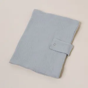 Vista detallada de la funda de cuaderno de gasa de algodón azul claro con correa de broche.