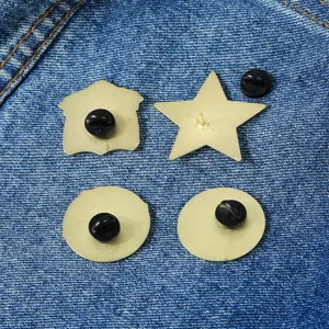 Metal brooch pin backs set, geometric shapes including star and circle on denim background.