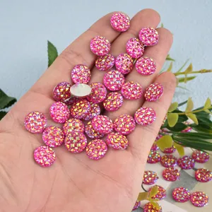 Close-up of sparkling pink round resin rhinestones in hand, perfect for DIY craft and art decor.