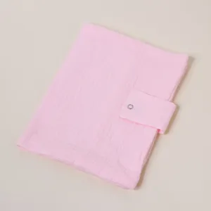Detalle de funda de libro de muselina de algodón rosa, estuche suave para cuaderno con botón.