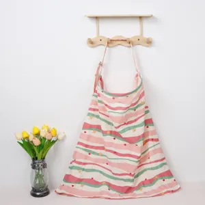 Detail view of printed cotton nursing cover hanging on wall hook with floral decor prop.