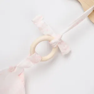Detail view of cotton nursing cover strap and wooden teething ring for baby care.