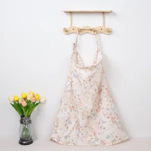 Detailed view of a soft floral cotton nursing cover hanging gracefully on a wooden rack.