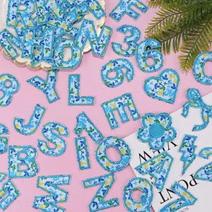 Detailed view of blue floral embroidered letter and shape patches, craft DIY accessory.