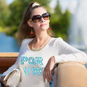 Detail view of white knitted sweater featuring stylish floral embroidered letter patches.