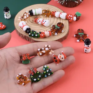Vue rapprochée de perles en verre de Noël faites main avec bonhomme de neige et sapin.