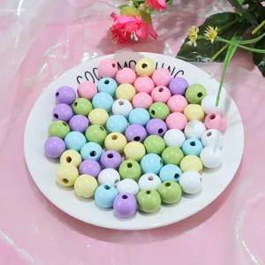 Gros plan de perles en bois pastel colorées dans une assiette blanche pour bijoux DIY.