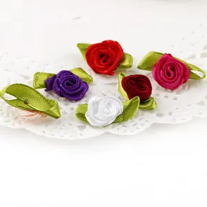 Handmade satin ribbon roses with green leaves, small fabric flower details for crafts clothing.