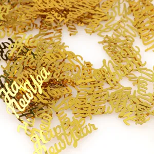 Detail view of gold plastic Happy New Year confetti scattered for holiday party decor.
