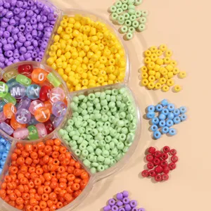 Gros plan de rocailles en verre colorées et perles alphabet dans une boîte de rangement.