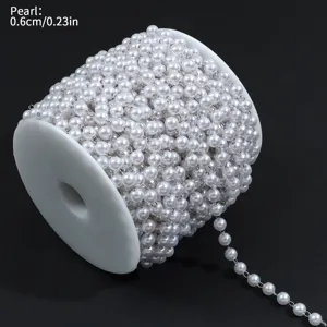 Vista detallada de cadena de perlas blancas en bobina para joyería artesanal.
