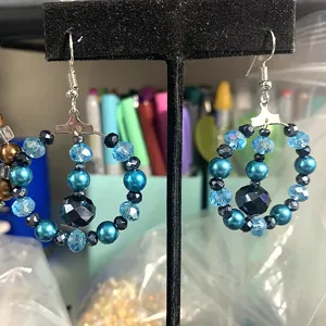 Vue détaillée de boucles d'oreilles créoles bleues perlées avec cristaux et perles sur support.