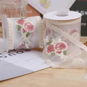 Detailed shot of delicate sheer ribbon with pink rose embroidery for DIY gift packaging.