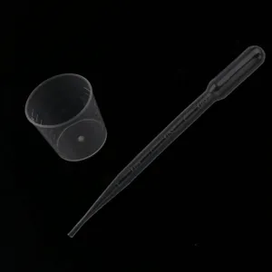 Detailed view of transparent plastic measuring cup and disposable dropper for DIY resin crafts.