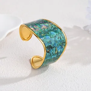 Detailed shot of wide C-shaped open cuff bracelet with green abalone pattern and gold edge.