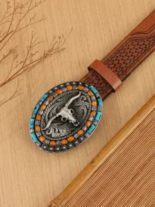 Close-up detail of western vintage bull skull belt buckle with turquoise beads and embossed strap.