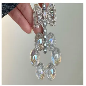 Vue détaillée de breloque de téléphone DIY en perles scintillantes nœud papillon.