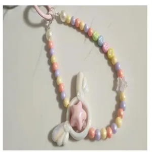 Pastel beaded phone charm with acrylic heart angel wings and custom letter beads for DIY decor.