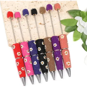 Detailed view of colorful beaded ballpoint pens with dazzling daisy rhinestones and metal tips.