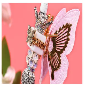 DIY pen accessory detail shot featuring pink fabric butterfly wings and rhinestones.