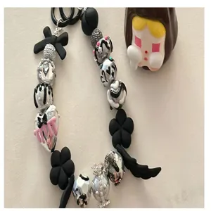 DIY black and white beaded phone charm strap with silver heart and flower pendants, stylish accessory.