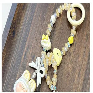 Detailed close-up of a handmade yellow and white beaded charm lanyard with a cute bow and pendant.