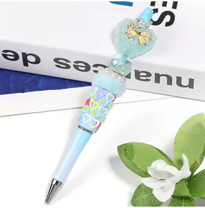 Detailopname van een decoratieve kralenpen, blauwe hartbedel met strik en pluche ringontwerp.