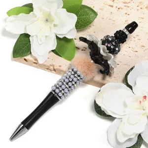 DIY beaded ballpoint pen featuring faux pearls, rhinestones and plush pom-pom design.