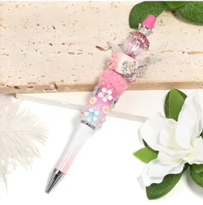 Close-up of a handmade rhinestone decorative beaded ballpoint pen with pink wings and floral charms.