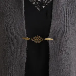 Primo piano dettaglio di clip per cardigan vintage bronzo intagliata per scialle e foulard.