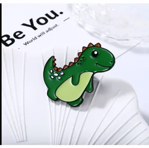Jolie broche émaillée dinosaure vert, badge de dessin animé détaillé pour vêtements.