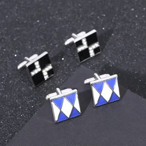 Gros plan de boutons de manchette carrés en métal avec strass et motifs émaillés.