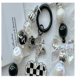Black and white acrylic beaded phone charm close-up, bow and checkered heart design detail.