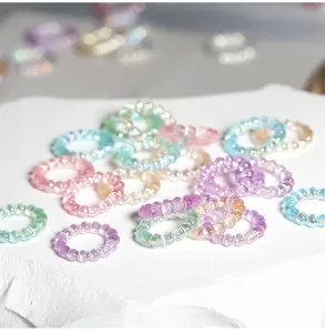 Primer plano detallado de anillos con cuentas translúcidas de colores y brillo iridiscente.