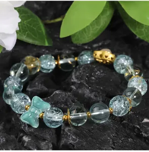 Detailed close-up of blue crackle glass beads and cute butterfly charm for DIY jewelry making.
