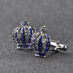 Gros plan détaillé de boutons de manchette couronne élégants avec des strass bleus.