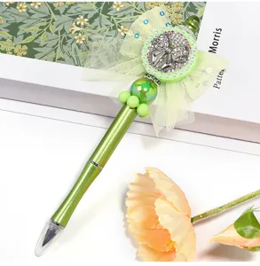 Detail van het decoratieve eeuwige potlood met strass-steentjes,strik en groene kralen.